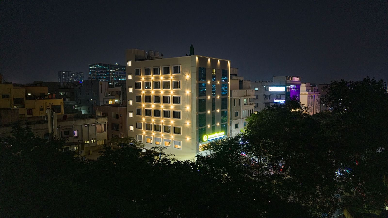 Lemonridge Hotels, KPHB | Exterior nighttime view of the hotel building, illuminated against the dark sky. Trees visible in foreground.